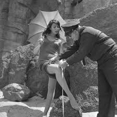 A cop measuring the length of a woman's bathing suit